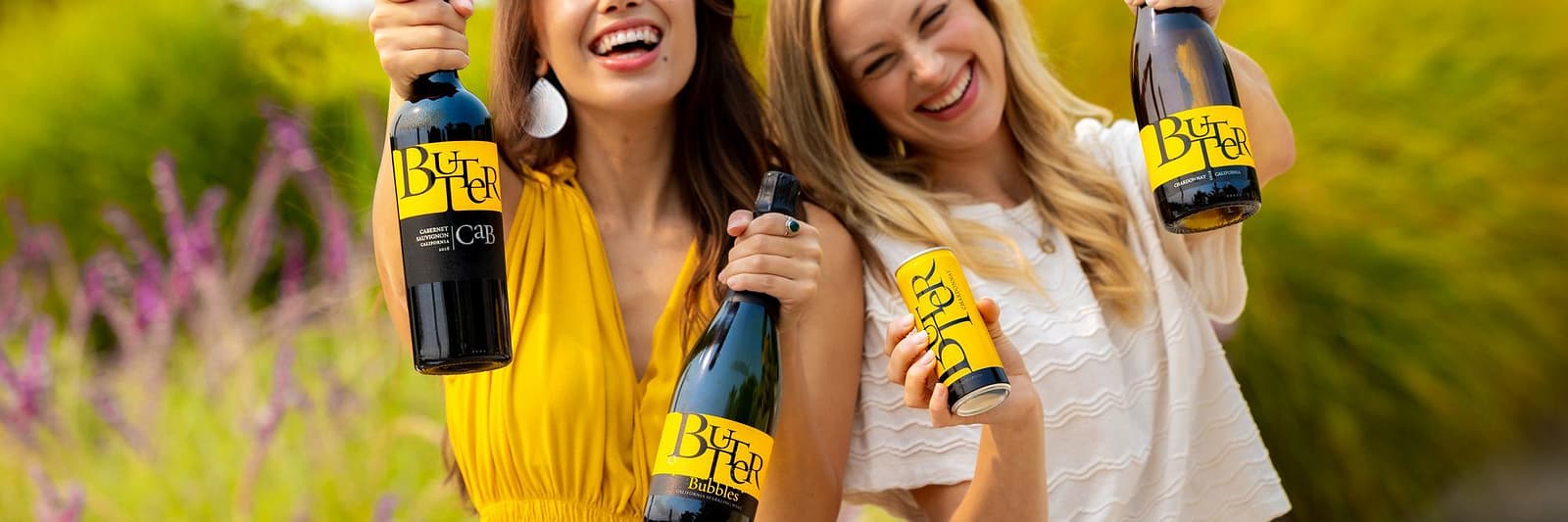 Butter Fam with two Butter Babes holding up the four bottles