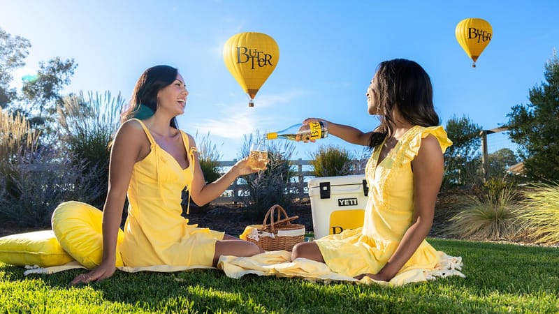 Two Butter Babes enjoying a bottle of ButterLight in Napa Valley under ButterLight Hot Air Balloons