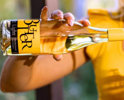 Butter Babe pouring a glass of the NEW Butter Light Chardonnay into her glass near friends.